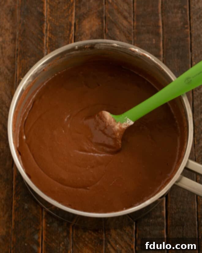 Stirring fudge until smooth before spreading into the prepared pan.
