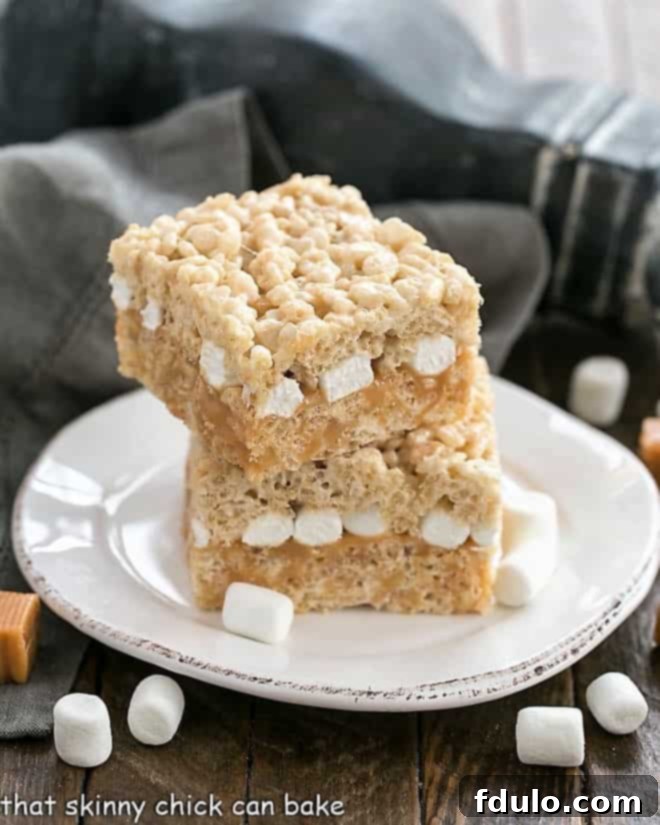 Two layers of crispy Rice Krispie Treats generously filled with gooey caramel, presented on a round dessert plate.