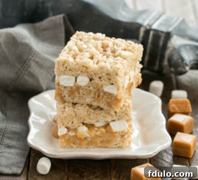 Stacked Caramel Stuffed Rice Krispie Treats showcasing their impressive layers and golden caramel filling on a square plate.