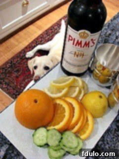 Pimm's Cup ingredients on the kitchen counter, including oranges, lemons, cucumber, mint, and a bottle of Pimm's No. 1
