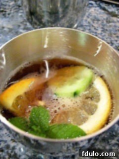 Pimm's Cup in a pewter cup with citrus, mint and cucumber garnish, ready to be enjoyed.