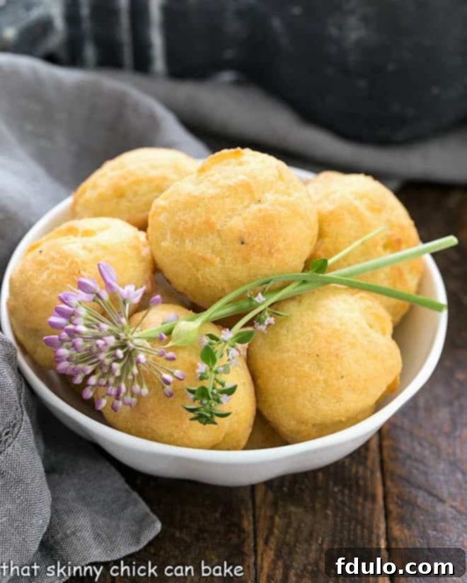 Gougères in a white bowl with herb garnishes.