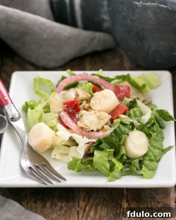 A perfectly arranged Italian Chopped Salad served on a square white plate with a fork, highlighting its vibrant colors and various textures.