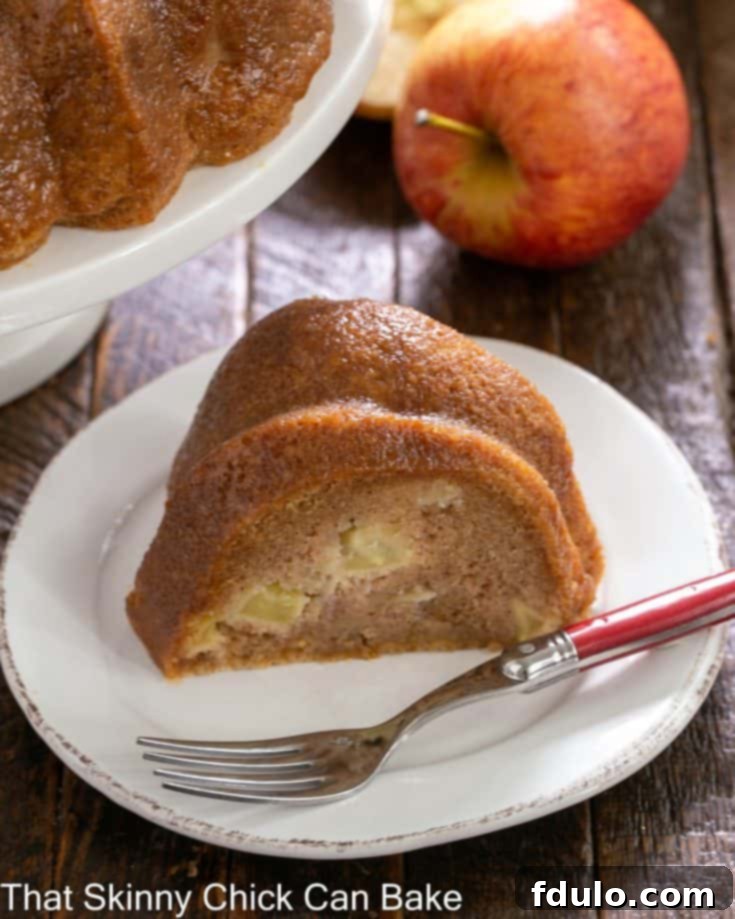 A beautifully decorated Apple Bundt Cake with a dusting of powdered sugar, presented on a rustic wooden board.