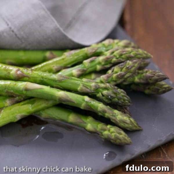 Oven Roasted Asparagus with Balsamic Brown Butter on a slate serving platter, showcasing its golden color and glossy sauce.