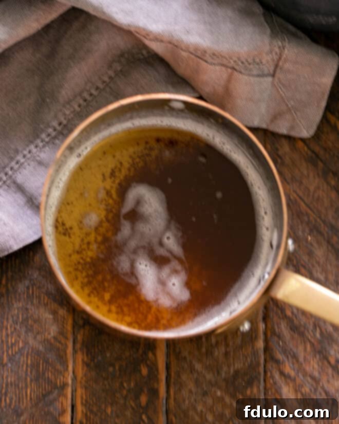 Overhead view of butter simmering in a saucepan, beginning to brown and release a nutty aroma.