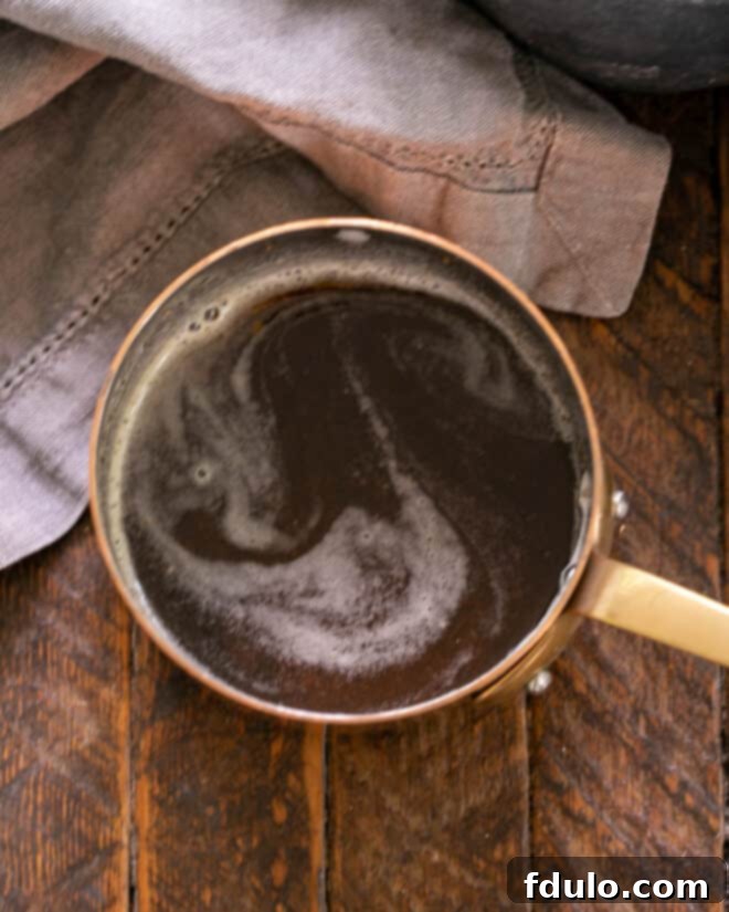 Overhead view of browned butter with soy sauce and balsamic vinegar being added, creating a rich sauce.