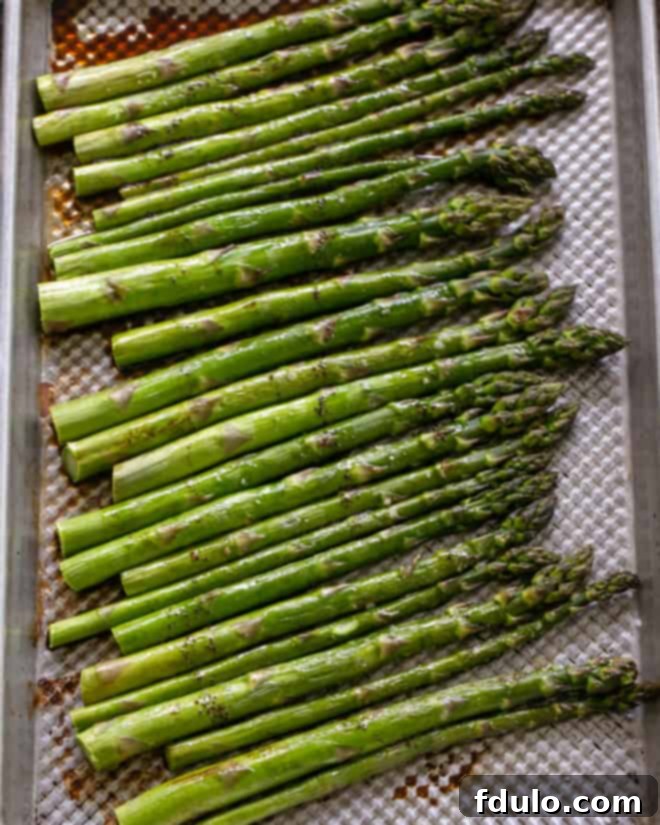 Roasted asparagus on a sheet pan, perfectly cooked and tender, ready for the sauce.