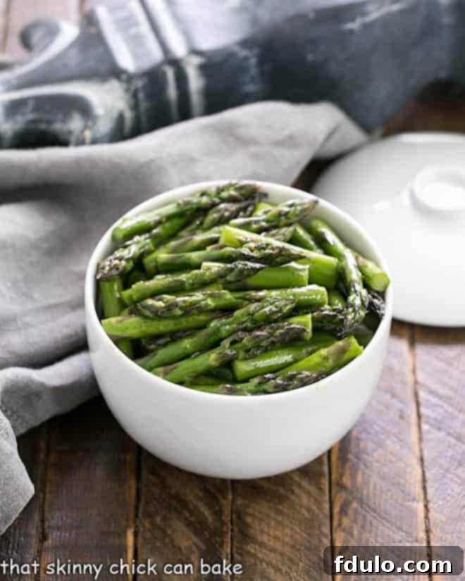 Oven roasted asparagus with balsamic brown butter served in a white ceramic bowl, garnished and ready to eat.