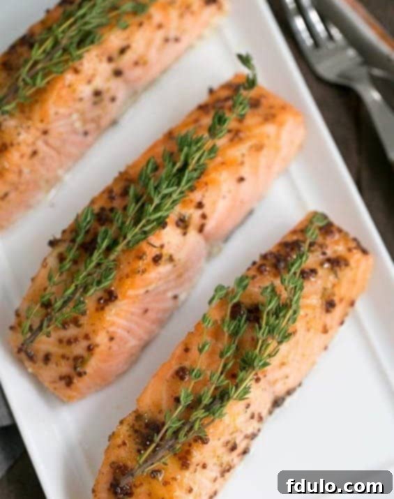 Cooked Maple Mustard Glazed Salmon on a serving tray, beautifully garnished with fresh sprigs of thyme.
