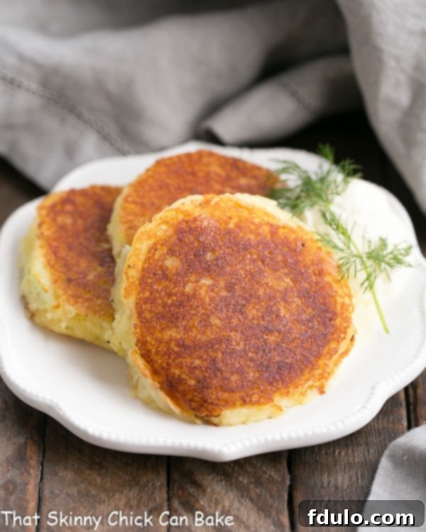 Gruyere Potato Cakes - Cheesy, herbed mashed potatoes fried to perfection Crispy Gruyere Potato Cakes arranged on a decorative white plate, ready to be served.