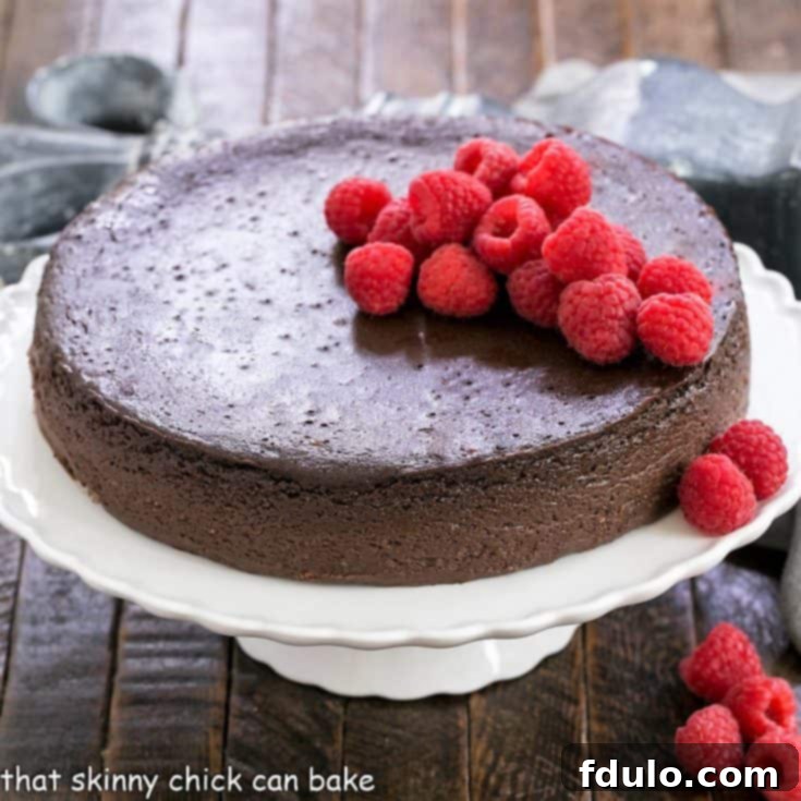 Flourless Kahlua cake on a white cake stand topped with raspberries