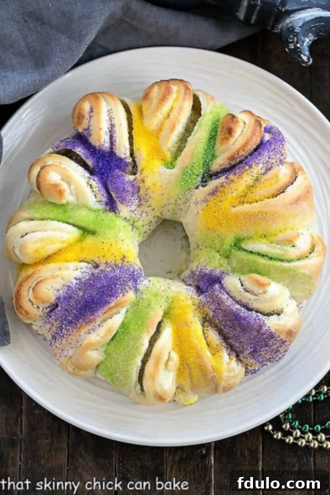 Easy King Cake with cream cheese filling on a round white serving dish viewed from above, showcasing the colorful sugars.