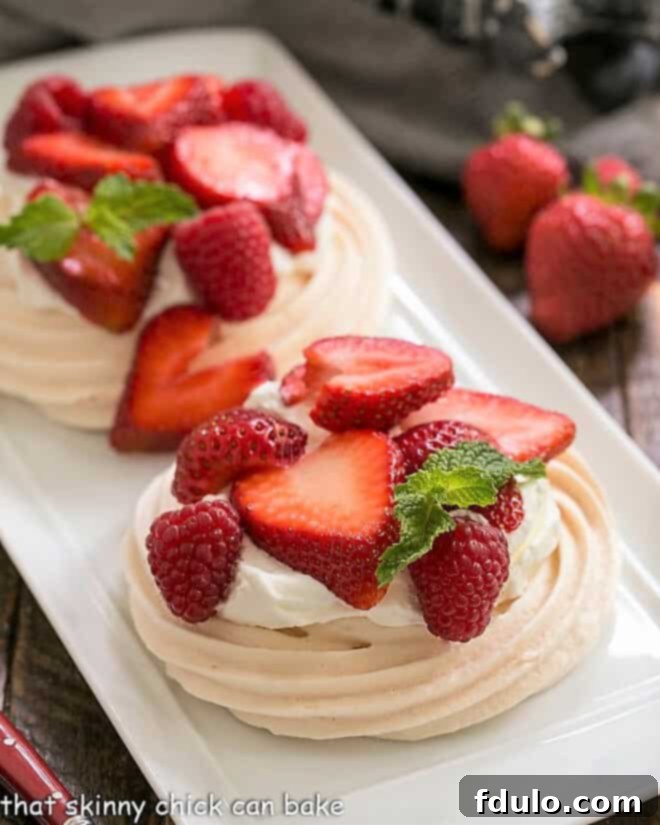Two individual pavlovas on a white tray, showcasing their elegant presentation and tempting toppings of whipped cream and fresh red berries.