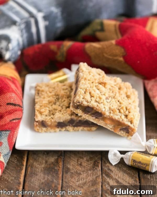 Two golden-brown Oatmeal Caramel Bars stacked on a square dessert plate, showcasing the gooey caramel and chocolate layers between the oat crust and streusel.