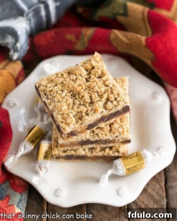 Overhead view of several Oatmeal Caramel Bars neatly stacked on a white dessert plate, highlighting the rich layers of oats, caramel, and chocolate.
