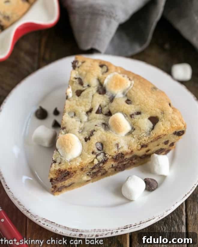A delectable wedge of Gooey Chocolate Chip Pie, showcasing its rich, melted chocolate chips and soft marshmallows, served on a crisp white dessert plate.