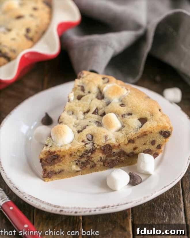 A perfect slice of Gooey Chocolate Chip Pie, showcasing its golden crust and melted chocolate and marshmallow interior, resting on a white ceramic plate.