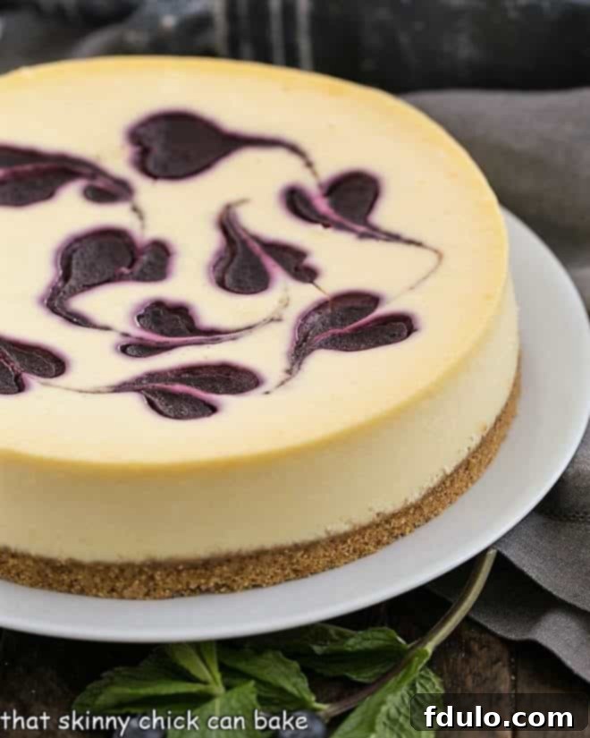 An uncut Blueberry Swirl Cheesecake sitting on an elegant white serving plate, ready to be chilled and enjoyed.