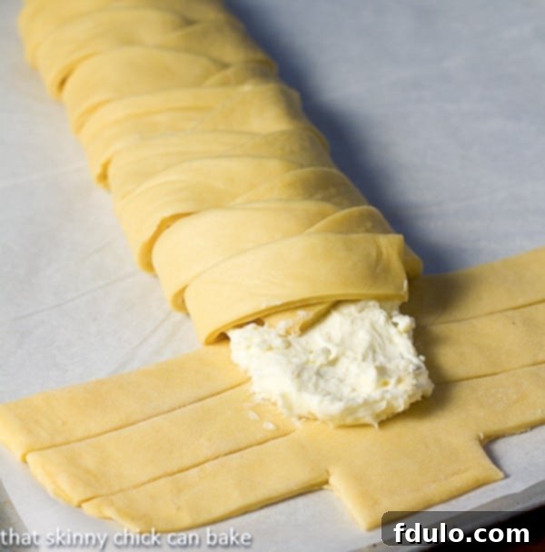 Close-up of plaited Easter Bread dough, showing the sliced strips being folded over the rich cream cheese filling.