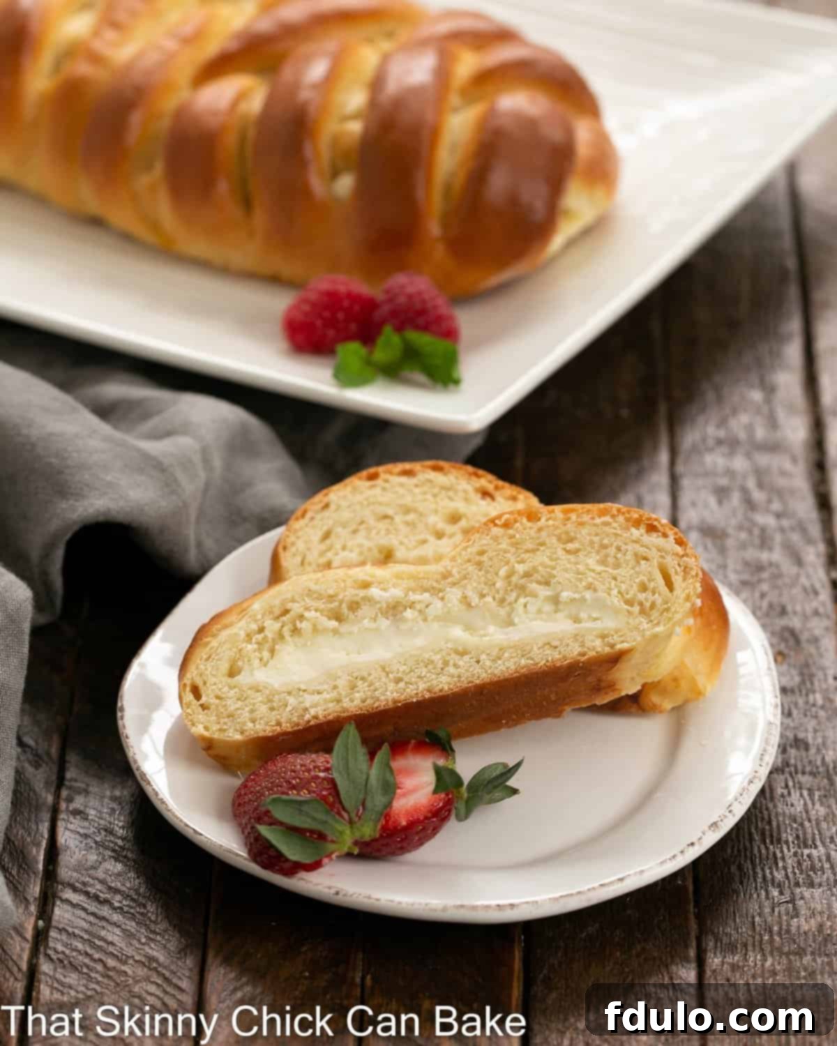 Beautifully presented slices of Plaited Easter Bread with cream cheese filling, arranged elegantly in front of a white serving tray.