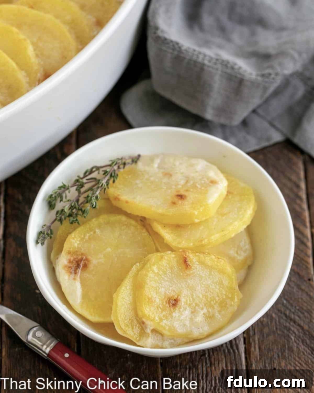 Close view of  a small bowl of scalloped potatoes next to the casserole dish.