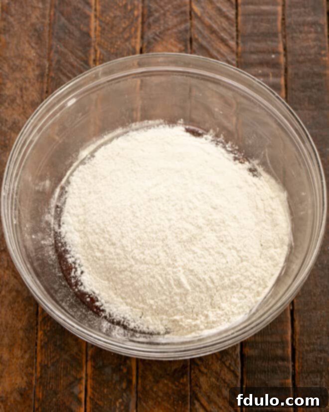 Step 5: Gradually mix in the dry ingredients (flour, baking powder, salt) into the wet chocolate mixture.