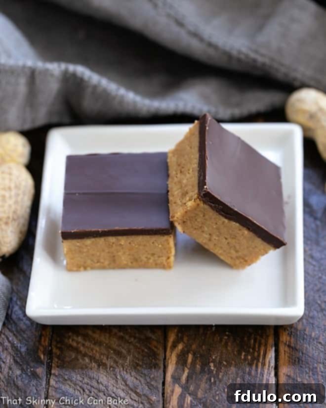 Several Better Than Reese's Peanut Butter Bars stacked neatly on a small square white plate, showcasing their distinct layers.