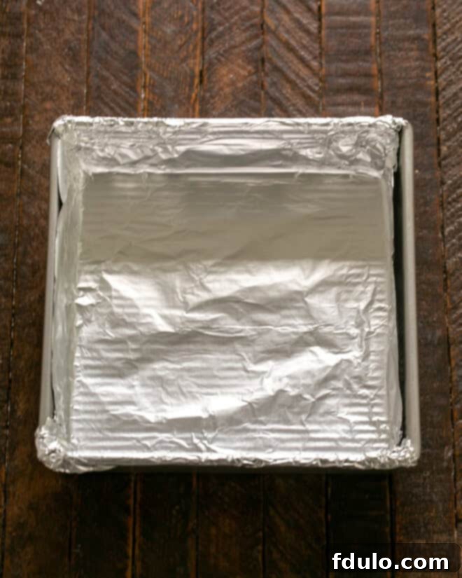 Step 1: Lining an 8x8 inch baking pan with non-stick foil for easy removal of peanut butter bars.