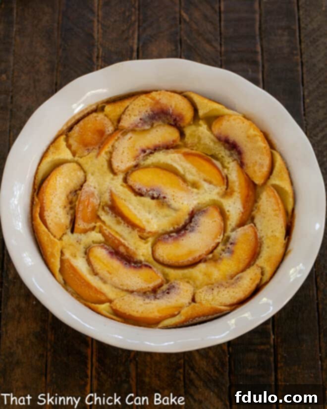 Fresh Peach Tart - A classic French dessert with a peach twist! A beautifully baked peach clafoutis in a white ceramic baking dish, golden brown and lightly puffed.