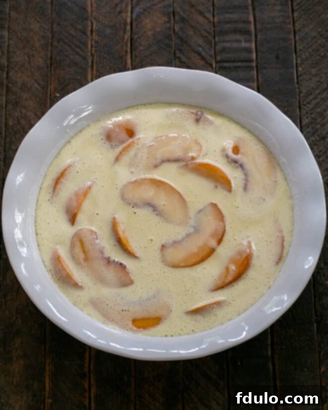Luscious Peach Clafoutis 5 The remaining clafoutis batter being poured over the peaches in the baking dish.