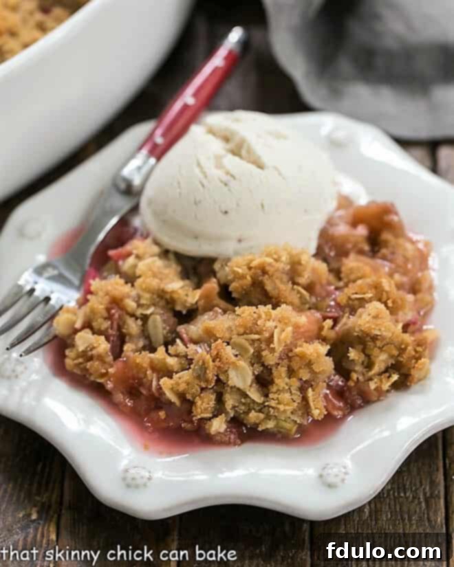 Close up view of easy rhubarb crisp on a white dessert plate, showing the texture of the crumble.