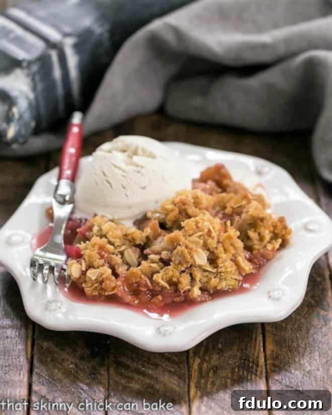 A serving of Easy Rhubarb Crisp on a white octagonal plate with a scoop of melting vanilla ice cream.