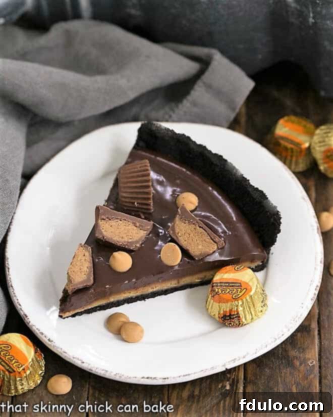 Reese's Peanut Butter Pie - Decadent layers of chocolate cookie crust, creamy peanut butter, and rich chocolate ganache. The ultimate no-bake dessert for Reese's lovers! A perfectly sliced piece of Reese's Peanut Butter Pie, showcasing its distinct layers of chocolate crust, peanut butter, and chocolate ganache, served on a crisp white plate.