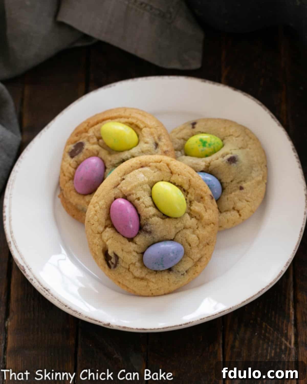 Overhead view of 3 Easter M&M Cookies on a white plate.