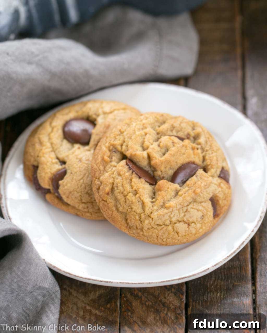 Brown Butter Chocolate Chip Cookies - with a boost of deliciousness from nutty brown butter and dark brown sugar! A perfectly baked Brown Butter Chocolate Chip Cookie resting on a pristine white dessert plate, inviting you to take a bite.