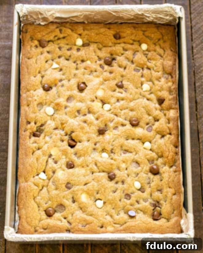 The cookie bars baking in the oven, showing a light golden-brown crust forming.