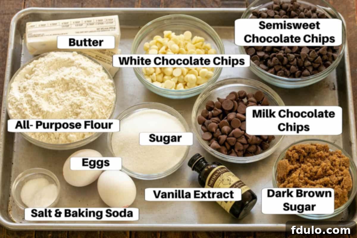 Overhead view of various chocolate chip cookie bar ingredients neatly arranged on a shiny metal sheet pan, complete with descriptive labels for each item.