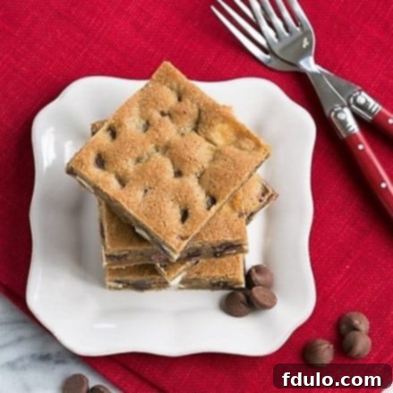 An overhead view of a perfectly baked stack of homemade chocolate chip bars, rich with various kinds of chocolate chips.