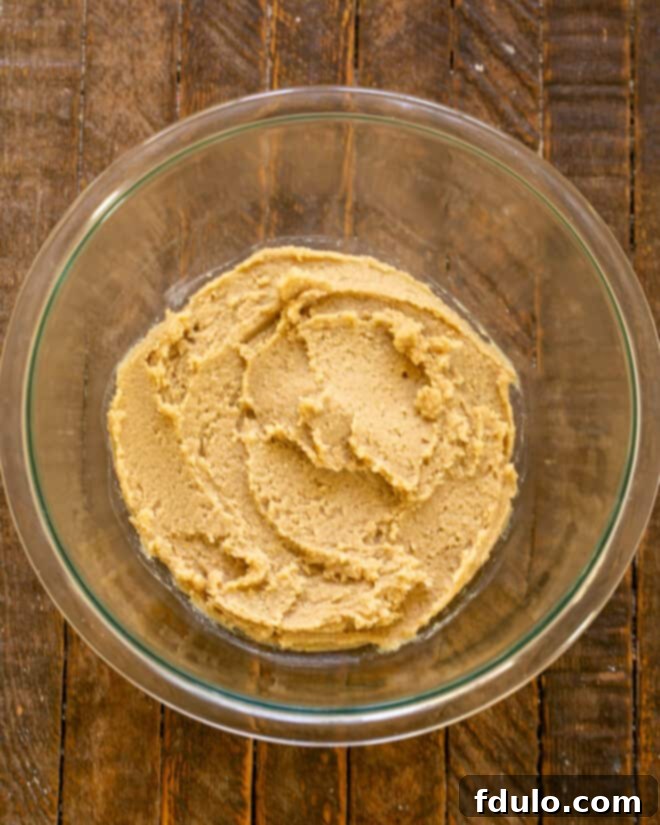 Butter and sugars being creamed together in a mixing bowl until light and fluffy.