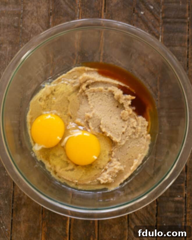 Eggs and vanilla extract being mixed into the creamed butter and sugar mixture.