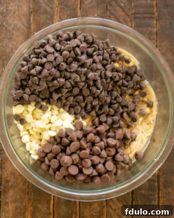 An abundance of chocolate chips being added to the prepared cookie dough.