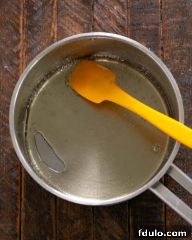Peanut Butter Chocolate Krispie Dream Bars 3 Image showing sugar, water, and corn syrup being heated in a saucepan to make sugar syrup.