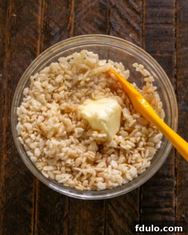 Peanut Butter Chocolate Krispie Dream Bars 4 Image showing the hot sugar syrup being poured over Rice Krispies cereal and melted butter in a large bowl.