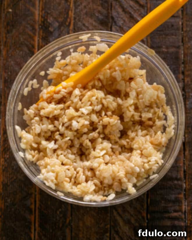 Peanut Butter Chocolate Krispie Dream Bars 5 Image showing the Rice Krispies mixture being thoroughly stirred until evenly coated.