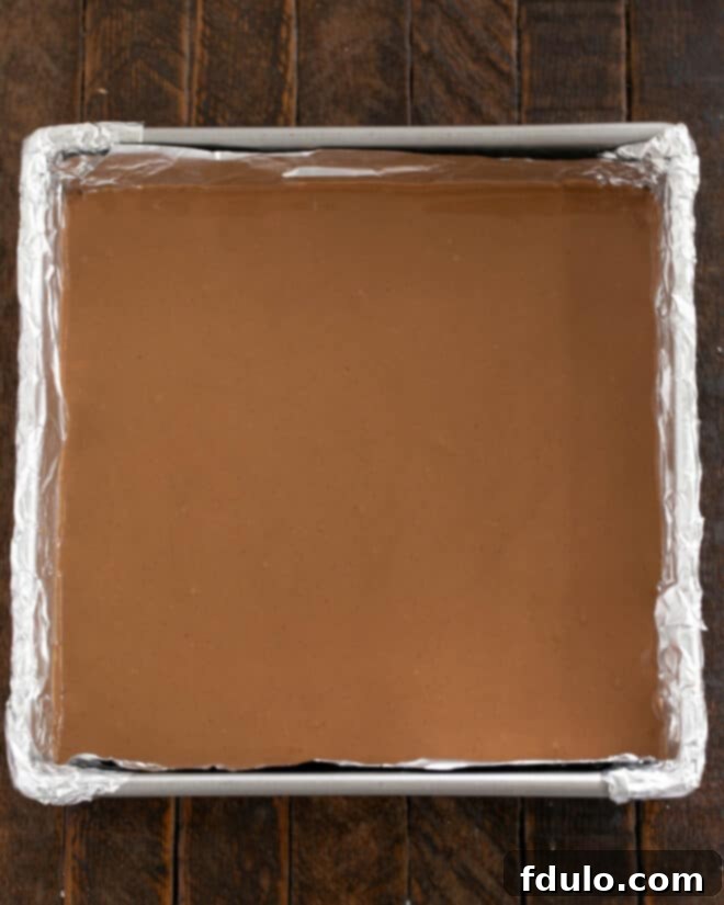 Peanut Butter Chocolate Krispie Dream Bars 7 Image showing the milk chocolate and peanut butter mixture being spread over the cooled Rice Krispies base.