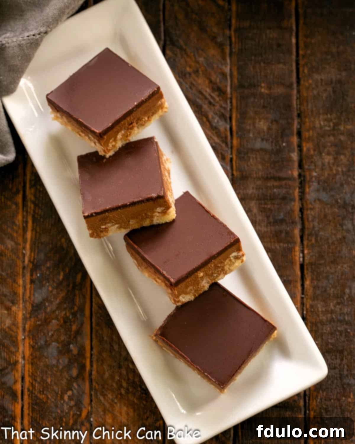 Peanut Butter Chocolate Krispie Dream Bars 9 Perfectly cut Peanut Butter Rice Krispie Treats arranged on a narrow white serving tray.