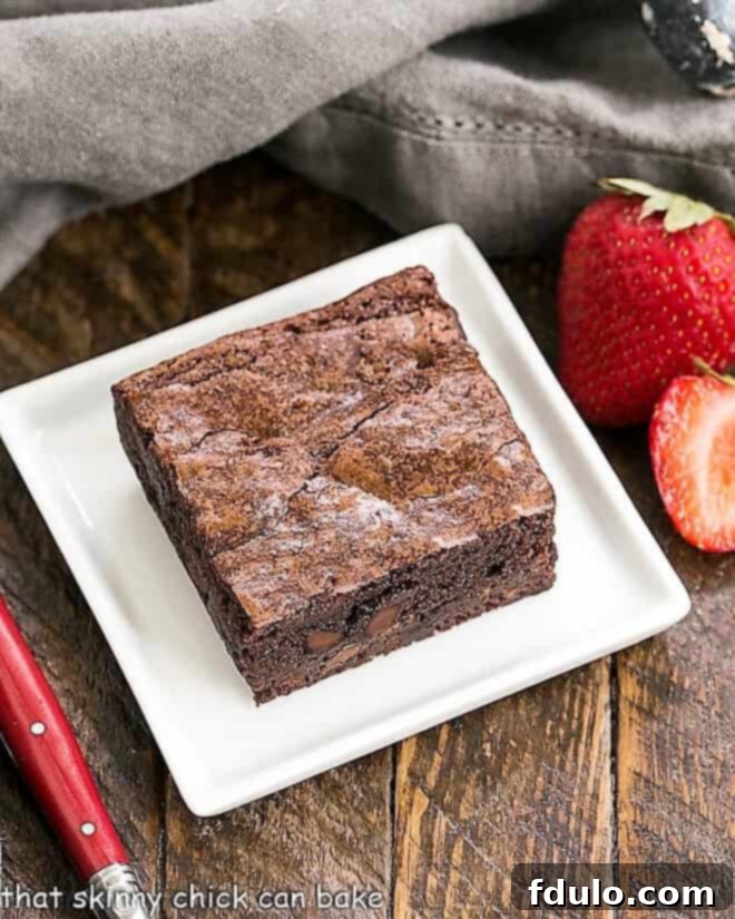 One fudgy sheet pan brownie on a square white plate, perfectly cut.