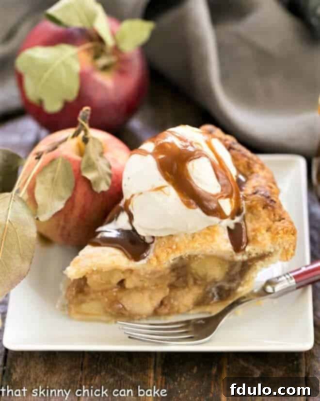 Caramel Apple Pie - a fabulous homemade apple pie enhanced by caramel sauce added to the filling! Caramel Apple Pie on a square white plate topped with ice cream and caramel sauce.