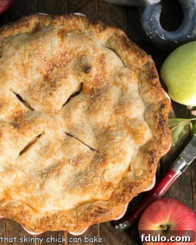 Caramel Apple Pie - a fabulous homemade apple pie enhanced by caramel sauce added to the filling! Overhead view of whole Caramel Apple Pie with apples and a red handle knife.